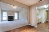 Located in Macon, GA (31210), this single-floor home offers a well-organized layout across multiple rooms. The living room is a standout feature, boasting vaulted ceilings that lend an open, airy feel, soft carpeting underfoot, and a classic fireplace with a white mantle as the focal point. Natural light filters in through windows and a glass door, brightening the space. Adjacent to the living room, a dining or flex area features wood-look flooring and connects seamlessly to the kitchen via a convenient pass-through window. The kitchen is equipped with light oak cabinetry, white countertops, a coil-burner electric range, and a refrigerator, providing practical functionality. A carpeted hallway with a textured ceiling connects the living areas to the private quarters. The bedrooms feature plush carpeting, ceiling fans with light kits, and neutral-toned walls, with windows providing natural light. Two full bathrooms each include a tub-shower combination, a toilet, a single-sink vanity with light oak cabinetry, a large mirror, and warm wood-look flooring. The overall aesthetic throughout the home is clean and neutral, offering a versatile canvas well-suited for a variety of interior styles.