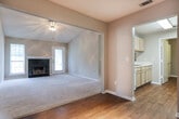 Located in Macon, GA (31210), this single-floor home offers a well-organized layout across multiple rooms. The living room is a standout feature, boasting vaulted ceilings that lend an open, airy feel, soft carpeting underfoot, and a classic fireplace with a white mantle as the focal point. Natural light filters in through windows and a glass door, brightening the space. Adjacent to the living room, a dining or flex area features wood-look flooring and connects seamlessly to the kitchen via a convenient pass-through window. The kitchen is equipped with light oak cabinetry, white countertops, a coil-burner electric range, and a refrigerator, providing practical functionality. A carpeted hallway with a textured ceiling connects the living areas to the private quarters. The bedrooms feature plush carpeting, ceiling fans with light kits, and neutral-toned walls, with windows providing natural light. Two full bathrooms each include a tub-shower combination, a toilet, a single-sink vanity with light oak cabinetry, a large mirror, and warm wood-look flooring. The overall aesthetic throughout the home is clean and neutral, offering a versatile canvas well-suited for a variety of interior styles.
