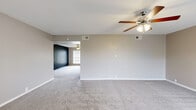 Located in Houston's 77079 zip code, this single-story, 2-bedroom, 2-bathroom home offers a well-designed layout with comfortable, functional living spaces throughout. The open-concept living area is generously sized, featuring plush neutral carpeting, a ceiling fan with integrated lighting, and large windows that flood the space with natural light and provide views of the surrounding greenery. A kitchen peninsula with granite countertops and white cabinetry adjoins the living area, creating a seamless flow ideal for everyday living and entertaining. The expansive primary bedroom is notably large, offering ample room for a full furniture arrangement, and is accented with a ceiling fan and soft carpeting. It connects to a dedicated walk-in closet outfitted with multi-level wire shelving systems for generous storage. Both bathrooms are finished with granite-topped vanities, wood-look tile flooring, and full tub-shower combinations with large-format stone-patterned tile surround. The secondary bedroom mirrors the neutral palette and carpeted comfort of the primary, with its own ceiling fan and a window for natural light. Warm gray tones, white trim, and consistent finishes unify the home's interior, lending a clean and cohesive aesthetic throughout.