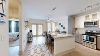 Located at 4320 Commons Drive West in Destin, FL, this well-appointed 1-bedroom, 1-bathroom residence offers a thoughtfully designed single-floor layout. The open-concept living, dining, and kitchen area serves as the heart of the home, bathed in natural light from large windows and French doors that lead to a private patio. Light wood-look flooring flows throughout the main living areas, complementing the bright, neutral color palette.

The kitchen is a standout feature, showcasing granite countertops, a large island with bar seating, white upper cabinetry paired with wood-toned lower cabinets, a classic subway tile backsplash, and a full suite of stainless steel appliances. Track and pendant lighting add a modern touch overhead. A pantry and dedicated laundry area provide convenient additional storage.

The living room is comfortable and airy, with large windows framing natural light and a ceiling fan overhead. The bedroom offers plush carpeting, a ceiling fan, natural light from a sizable window, and two closets for ample storage. The bathroom features a wood-toned vanity with granite countertop, a soaking tub with marble-style tile surround, and wood-look flooring. A hallway connects the private spaces seamlessly, completing this efficient and stylish Destin residence.
