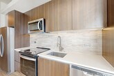 Located at 1500 Westbranch Drive in McLean, VA, this thoughtfully designed one-bedroom, one-bathroom residence offers a modern and efficient layout across a single floor. Light-toned hardwood-style flooring flows throughout, complementing the bright, neutral color palette and creating a cohesive, contemporary ambiance.

The open-concept living, dining, and kitchen area serves as the heart of the home, bathed in natural light from large windows with views to a private balcony. The kitchen is a standout feature, showcasing rich wood-grain cabinetry extending to the ceiling, white quartz countertops, a textured tile backsplash, and a full suite of stainless steel appliances including a range, microwave, dishwasher, and refrigerator — all finished with brushed nickel hardware.

A welcoming hallway connects the main living space to the private bedroom, which is serviced by two closets offering generous storage. An in-unit laundry area adds everyday convenience. The bathroom features a glass-enclosed walk-in shower clad in elegant marble-style porcelain tile, lending a spa-like quality to the space. Clean white walls and crisp trim complete the polished, move-in-ready aesthetic of this well-appointed McLean residence.