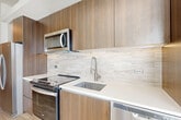 Located at 1500 Westbranch Drive in McLean, VA, this thoughtfully designed one-bedroom, one-bathroom residence offers a modern and efficient layout across a single floor. Light-toned hardwood-style flooring flows throughout, complementing the bright, neutral color palette and creating a cohesive, contemporary ambiance.

The open-concept living, dining, and kitchen area serves as the heart of the home, bathed in natural light from large windows with views to a private balcony. The kitchen is a standout feature, showcasing rich wood-grain cabinetry extending to the ceiling, white quartz countertops, a textured tile backsplash, and a full suite of stainless steel appliances including a range, microwave, dishwasher, and refrigerator — all finished with brushed nickel hardware.

A welcoming hallway connects the main living space to the private bedroom, which is serviced by two closets offering generous storage. An in-unit laundry area adds everyday convenience. The bathroom features a glass-enclosed walk-in shower clad in elegant marble-style porcelain tile, lending a spa-like quality to the space. Clean white walls and crisp trim complete the polished, move-in-ready aesthetic of this well-appointed McLean residence.