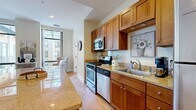 This thoughtfully designed 3-bedroom, 2-bathroom residence offers a highly functional single-floor layout that maximizes every square foot. The open-concept kitchen and living area serves as the heart of the home, featuring warm medium-toned wood cabinetry, granite countertops, stainless steel appliances including a gas range and built-in microwave, and a peninsula island with bar seating — ideal for casual dining or entertaining. Light hardwood flooring flows throughout the common areas, complementing the bright, neutral palette.

The living room is a standout space, bathed in abundant natural light through dramatic floor-to-ceiling windows that frame views of the surrounding building exterior. The airy, open feel is further enhanced by recessed lighting and generous ceiling height.

The primary bedroom is a comfortable retreat, featuring plush wall-to-wall carpeting, access to outdoor views via large sliding glass doors, and a dedicated walk-in closet with built-in shelving. The two bathrooms are well-appointed with warm wood vanities, white countertops, tub-shower combinations, and tile flooring. Additional bedrooms offer carpeted floors and ample natural light. The overall ambiance is clean, modern, and move-in ready.