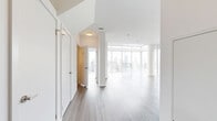 Located in the heart of downtown Toronto, this two-bedroom, two-bathroom two-storey residence at 55 Gerrard St W offers a sophisticated urban living experience. The main floor is anchored by a bright, open-concept living area with soaring double-height ceilings and expansive floor-to-ceiling windows that frame breathtaking panoramic views of the Toronto skyline, flooding the space with natural light. The modern kitchen is thoughtfully designed with two-tone cabinetry in white and grey, a tiled backsplash, stainless steel appliances including a full-size refrigerator, a central island with a quartz countertop, and a stylish pendant light fixture. The upper floor hosts the bedrooms, including a generously sized primary bedroom with corner floor-to-ceiling windows offering striking city views, complemented by a dedicated walk-in closet with built-in shelving and rails. The primary ensuite bathroom features a double vanity with quartz countertops, backlit mirrors, and a glass-enclosed shower. A second well-appointed bathroom includes a single vanity, backlit mirror, and a soaker tub. Throughout the unit, wide-plank hardwood flooring adds warmth and continuity, while the clean white palette creates a bright, contemporary ambiance.