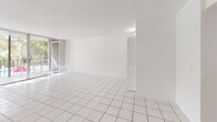 Located in Coral Springs, Florida, this well-appointed 2-bedroom, 2-bathroom residence offers a clean, bright, and efficiently designed single-floor layout. White square tile flooring runs throughout the entire space, creating a cohesive and easy-to-maintain interior that reflects Florida's sunny climate.

The open-plan combined dining and living area is generously sized, bathed in natural light from floor-to-ceiling sliding glass doors that lead directly to a private balcony. The balcony overlooks a pool area framed by mature trees, offering a pleasant outdoor retreat. A textured ceiling adds a subtle design detail to the living space.

The kitchen features white cabinetry, granite-style countertops, stainless steel appliances including a range, dishwasher, and refrigerator, as well as a skylight that enhances natural brightness. A dedicated laundry area with a full-size washer and dryer adds everyday convenience.

The primary bedroom is spacious and well-lit, benefiting from large windows with outdoor views and an expansive wall of sliding closet doors offering generous storage. A second bedroom provides additional flexible living space. Both bathrooms are finished with white tile, including a full tub-shower combination. Four closets throughout the unit ensure ample storage. The entrance hallway connects all areas of the home in a practical and organized flow.