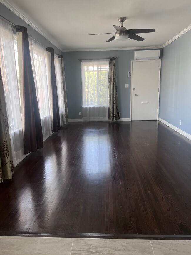 Living room with large windows and original wood floors. - 11346 Califa St