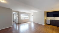 Located in the heart of downtown Dallas at 300 S St Paul St, this modern single-floor residence combines contemporary design with functional living. Rich hardwood flooring flows throughout the open living and dining areas, reflecting natural light that pours in through large windows framing views of the surrounding cityscape. The spacious living area offers a clean, neutral palette with smooth white ceilings and crisp baseboards, creating a bright and airy atmosphere.

The kitchen is outfitted with dark espresso-toned cabinetry that extends to the ceiling, a full suite of stainless steel appliances including a french door refrigerator, a range, microwave, and dishwasher, all set against white countertops and a sleek backsplash. The bedroom features continued hardwood flooring and includes a closet with built-in shelving for ample storage.

The unit includes multiple bathrooms. One full bathroom offers a soaking tub and shower combination with white tile surround, a dark wood vanity, white countertop, and a backlit mirror. A second full bathroom features a frameless glass walk-in shower with a rainfall showerhead and matching vanity. A dedicated water closet provides additional convenience, finished with large-format stone-look wall tile for a refined touch.
