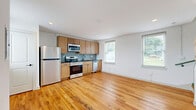 Located at 223-225 Henry St in Petersburg, VA, this two-floor residence offers a thoughtfully laid-out 1-bedroom, 1-bathroom floor plan spread evenly across two levels. Warm hardwood floors run throughout the space, lending a consistent and inviting character to every room.

The main floor hosts an open-concept kitchen and living area, allowing for a flexible and functional living arrangement. The kitchen is well-appointed with light wood cabinetry, dark countertops, a herringbone-patterned tile backsplash in a soft blue-gray tone, and a full suite of stainless steel appliances including a refrigerator, range, microwave, and dishwasher. Multiple windows flood the space with natural light and offer views of the surrounding greenery.

The upper floor is dedicated to the spacious primary bedroom, which is notably generous in size and features multiple windows along one wall, maximizing natural light and outdoor views. Two closets provide ample storage. A dedicated laundry area adds everyday convenience.

The bathroom features classic penny tile flooring and clean white finishes, maintaining a timeless aesthetic. The overall design of the space is clean and modern, with white walls and simple trim that complement the warmth of the hardwood floors throughout.
