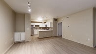 Located at 12500 Merit Dr in Dallas, TX, this one-bedroom, one-bathroom unit offers a well-designed layout across a single floor. The open-concept living and kitchen area serves as the heart of the home, featuring light wood-style flooring, neutral warm-toned walls, and track lighting that brightens the space. The kitchen is well-appointed with white shaker-style cabinetry, white quartz countertops, a tan subway tile backsplash, and a full suite of stainless steel appliances including a range, microwave, dishwasher, and refrigerator. A kitchen island provides additional counter space and a natural divide from the living area. The living room offers a clean, open feel with access to multiple closets and an entry area with convenient storage doors. The bedroom is carpeted and includes a ceiling fan, vertical blinds, and access to a generously sized walk-in closet with wire shelving on multiple walls. The full bathroom features a wide vanity with white cabinetry, a large mirror, brushed nickel fixtures, and a tiled tub-shower combination. A dedicated laundry area houses a full-size washer with overhead wire shelving, adding everyday convenience to this efficiently designed Dallas residence.