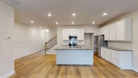 Located at 2367 Whitburn Road in Lawrenceville, GA, this well-appointed two-story home offers four bedrooms and four bathrooms across two thoughtfully designed floors. The main level features an open-concept kitchen and living area bathed in recessed lighting, with warm hardwood-style flooring flowing throughout. The kitchen is a standout, boasting granite countertops, white shaker cabinetry, stainless steel appliances including a built-in microwave and refrigerator, and a central island with a sink — ideal for both everyday living and entertaining. A staircase with wood balusters connects the main floor to the upper level, where a hallway with elegant wainscoting panels leads to the four bedrooms. The bedrooms feature plush carpet flooring, recessed lighting, and windows that invite natural light and neighborhood views. The primary bedroom is generously sized and includes a dedicated closet with wire shelving systems. The bathrooms are finished with granite-topped dual-sink vanities, white cabinetry, and glass-enclosed showers. Three closets provide practical storage throughout. The home's neutral color palette, consistent finishes, and clean architectural lines create a bright, modern, and cohesive living environment.