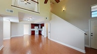 This two-story, 3-bedroom, 2-bathroom townhome is thoughtfully designed to maximize comfort and functionality. The main level features an open-concept living and dining area with warm hardwood-style flooring that flows throughout. A dramatic two-story ceiling in the main living space, overlooked by an upstairs balcony railing, creates a striking sense of openness and volume. Ceiling fans are present throughout the home for added comfort. The kitchen is equipped with rich cherry wood cabinetry, granite-style countertops, a double stainless steel sink, and white appliances including a range, built-in microwave, and dishwasher. A full bathroom on the main level features tile flooring, a vanity with a dark wood cabinet, and a tub-shower combination. Upstairs, three carpeted bedrooms provide comfortable retreats, each featuring ceiling fans and windows that allow natural light. The primary bedroom is generously sized with sliding glass door access and an en-suite bathroom featuring a separate glass-enclosed shower, a soaking tub, granite countertops, and tile flooring. The additional bedrooms are well-proportioned with ample closet access. Neutral warm tones throughout the home create a cohesive and inviting atmosphere.