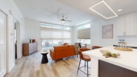 Located at 1002 N Fourth St in Flagstaff, AZ, this thoughtfully designed one-bedroom, one-bathroom residence offers a clean, contemporary aesthetic across a single-level floor plan. Light-toned hardwood flooring flows seamlessly throughout, unifying each space with a warm, cohesive feel.

The open-concept kitchen and living area serves as the heart of the home. The kitchen is outfitted with white upper cabinetry, dark lower cabinets, white quartz countertops, a subway tile backsplash, stainless steel appliances — including a refrigerator, range, and microwave — and a center island with bar seating, illuminated by a sleek rectangular pendant light. The living room is bright and airy, featuring expansive floor-to-ceiling sliding glass doors and transom windows that flood the space with natural light and open directly to a private outdoor balcony.

The bedroom is a comfortable retreat, finished with the same light hardwood flooring, a sliding-door closet, a ceiling fan, and a window offering views of the surrounding neighborhood. The bathroom is clean and modern, featuring white shaker-style cabinetry, a quartz vanity top, a backlit mirror, and large-format tile flooring. This well-appointed residence combines functional design with contemporary style in the heart of Flagstaff.