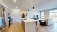 Located at 4607 Monona Dr in Monona, WI, this thoughtfully designed 2-bedroom, 2-bathroom residence offers a comfortable and modern single-floor layout. The open-concept living, dining, and kitchen area forms the heart of the home, where light wood-tone flooring, neutral tones, and recessed lighting create a clean, contemporary atmosphere. The kitchen is a standout feature, showcasing sleek grey cabinetry, stainless steel appliances, a white quartz island with bar seating, a subway tile backsplash, and stylish pendant lighting overhead. The living area is bathed in natural light through large sliding glass doors that open to a private balcony, offering outdoor views. The primary bedroom is a well-proportioned retreat with plush carpeting and closet space, while the second bedroom features large windows and a ceiling fan. Both bathrooms are finished with modern grey cabinetry, white quartz countertops, and matte black hardware; the primary bath offers a long vanity, while the secondary bath includes a full tub-shower combo. Three closets provide ample storage throughout. A dedicated in-unit laundry room houses a full-size stacked washer and dryer, adding everyday convenience to this well-appointed home.