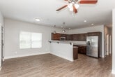 Located at 1805 Shiloh Rd NW in Kennesaw, Georgia, this two-story home offers a thoughtfully designed layout across two levels. The main floor welcomes you through a bold dark front door with a glass accent panel, opening into a bright, open living area bathed in natural light from multiple windows dressed with white blinds. Rich wood-look flooring extends throughout the main level, creating a warm and cohesive aesthetic. The kitchen is a standout feature, showcasing deep espresso-toned cabinetry, granite countertops, stainless steel appliances including a range, microwave, and dishwasher, and warm pendant lighting — all centered around a generous U-shaped layout ideal for cooking and entertaining. A convenient half bath on the main floor features dark cabinetry with a granite vanity top and wood-look flooring. Upstairs, the bedrooms are finished with plush carpeting, ceiling fans, and dark five-panel doors that add a modern touch. The upper-level bathrooms are well-appointed with dark vanities, granite countertops, and tub-shower combinations. A staircase with decorative iron railings connects both floors, adding an architectural detail visible from the open-concept dollhouse view of the home.