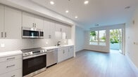 Located in the vibrant Park Boulevard corridor of San Diego's 92103 neighborhood, this thoughtfully designed one-bedroom, one-bathroom unit offers a clean, contemporary living experience across a single floor. Light-toned hardwood-style flooring runs throughout, unifying each space with a warm, cohesive aesthetic.

The open-concept kitchen is a standout feature, outfitted with gray shaker-style cabinetry, a herringbone-patterned tile backsplash, white quartz countertops, and a full suite of stainless steel appliances including a French door refrigerator, electric range, built-in microwave, and dishwasher. Recessed lighting illuminates the space, which flows seamlessly into the living area. A large window in the living room fills the space with natural light and frames views of lush outdoor greenery.

The bedroom is a bright, serene retreat with a tall window overlooking palm trees and neighboring architecture. It is served by a dedicated walk-in closet featuring multi-tiered shelving and hanging rods, offering generous storage capacity.

The bathroom features floor-to-ceiling large-format gray tile surrounding a deep soaking tub with an integrated shower and brushed gold fixtures, lending a spa-like quality to the room.

A hallway nook houses a stacked in-unit washer and dryer, adding everyday convenience to this well-appointed San Diego residence.