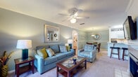 This single-story, 2-bedroom, 2-bathroom residence is thoughtfully designed with a cohesive color palette of soft blue-gray tones, neutral carpeting, and warm wood-look flooring that carries throughout key areas. The living room serves as the central gathering space, featuring crown molding, a ceiling fan, and a framed mirror accent wall. French doors open to an outdoor area, filling the room with natural light. The space flows seamlessly into a dedicated dining area, distinguished by chair-rail molding, decorative wall art, and a stylish sunburst mirror.

The galley-style kitchen is efficiently laid out with white cabinetry, white appliances, and warm hardwood-style flooring that maximizes functionality. Both bedrooms are generously sized with plush carpeting, ceiling fans, and multiple windows providing ample natural light. One bedroom features a walk-in closet with built-in shelving, while the other includes multiple windows on two walls. The bathrooms are finished with white vanity cabinetry, large mirrors, and hardwood-style flooring. The floorplan model reveals a well-organized layout that balances open communal spaces with private retreats.
