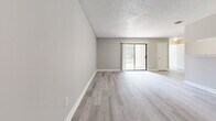 This 2-bedroom, 2-bathroom single-floor residence at 4901 Bottlebrush Ln in Orlando, Florida offers a clean, modern aesthetic throughout. Light-toned luxury vinyl plank flooring runs consistently across all rooms, complemented by neutral gray walls and crisp white baseboards that create a bright, cohesive feel.

The open living room is a comfortable, well-proportioned space featuring a textured popcorn ceiling and a sliding glass door that invites natural light and provides direct access to the outdoors. The galley-style kitchen is efficiently laid out with white cabinetry, light granite-style countertops, a stainless sink, and white appliances including a range and refrigerator.

The primary bedroom is a generously sized retreat with a dedicated closet, while the second bedroom features a large window with blinds that frames a green outdoor view, filling the room with natural light. Both bathrooms are finished consistently, each offering a tub/shower combination, white vanity cabinetry with granite-style countertops, and matching flooring. A dedicated entrance and additional closet round out the layout. The overall ambiance is clean, neutral, and move-in ready, offering a practical and comfortable living environment in Orlando.