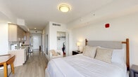 Located on the sixth floor at 1025 E 25th St in Hialeah, Florida, this thoughtfully designed one-bedroom, one-bathroom unit offers a modern living experience with a clean, contemporary aesthetic throughout. Light wood-toned flooring and crisp white walls create a bright, airy atmosphere that flows seamlessly from room to room.

The bedroom is generously proportioned, serving as the heart of the unit. It features large sliding glass doors that open to a private balcony, filling the space with abundant natural light and offering open city views of the surrounding Hialeah skyline. The room comfortably accommodates a full bedroom suite and a small dining area, making it highly versatile.

The kitchen is efficiently designed with light wood cabinetry, white quartz countertops, a white subway tile backsplash, and stainless steel LG appliances, including a range, over-the-range microwave, and an integrated washer. A single-basin sink with a modern chrome fixture completes the space.

The bathroom is elegantly finished with floor-to-ceiling marble-look tile surrounding a full soaking tub and glass-enclosed shower combo. White cabinetry and neutral tile flooring contribute to a clean, spa-like feel. Additional spaces include a closet and hallway, ensuring practical storage and a well-organized layout throughout this efficiently planned unit.