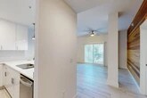 Located in Jacksonville Beach, FL, this well-appointed single-floor residence offers 2 bedrooms, 2 bathrooms, a den, and a dedicated laundry area across a thoughtfully designed layout. The open-concept living, dining, and kitchen area serves as the heart of the home, highlighted by light-toned tile flooring and a bold horizontal wood-plank accent wall that adds warmth and texture to the space. Sliding glass doors and plantation-shuttered windows flood the living area with natural light, while a ceiling fan adds to the coastal ambiance.

The kitchen features sleek white cabinetry, a white subway tile backsplash, quartz countertops, stainless steel appliances including a refrigerator and dishwasher, and pendant lighting over the extended breakfast bar — a clean, modern aesthetic throughout.

Both bedrooms are carpeted and feature ceiling fans, with ample closet access. The primary bedroom connects directly to its own bathroom, which showcases large-format tile flooring, a white vanity with quartz countertop, brushed gold fixtures, and a glass-enclosed walk-in shower with floor-to-ceiling tile surround. The second bathroom mirrors this refined design. With four closets and a dedicated den, this residence provides generous storage and flexible living options.