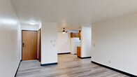 Located at 5401 W 26th St in Sioux Falls, South Dakota, this two-bedroom, one-bathroom unit offers a practical and comfortable layout across a single floor. The open living room is bright and airy, featuring light-toned luxury vinyl plank flooring, a ceiling fan, and a large sliding glass door that leads to a private balcony, allowing natural light to fill the space. A wall-mounted HVAC unit provides convenient climate control directly in the living area.

The galley-style kitchen is efficiently designed with warm wood cabinetry lining both walls, offering generous upper and lower storage. A double-basin sink, a range, and a full-size refrigerator complete the functional layout, all finished with light vinyl plank flooring.

Both bedrooms are carpeted with a patterned multi-tone grey carpet and are equipped with ceiling fans. The primary bedroom benefits from a window with blinds, allowing for natural light and outdoor views. Each bedroom includes closet access, and the unit features three closets in total for ample storage throughout.

The bathroom is clean and well-appointed, featuring a full tub/shower combo with white surround, a wood-vanity with a light countertop, and coordinating black hardware accents. Light vinyl plank flooring ties the bathroom's aesthetic together with the rest of the unit.