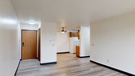 Located at 5401 W 26th St in Sioux Falls, South Dakota, this two-bedroom, one-bathroom unit offers a practical and comfortable layout across a single floor. The open living room is bright and airy, featuring light-toned luxury vinyl plank flooring, a ceiling fan, and a large sliding glass door that leads to a private balcony, allowing natural light to fill the space. A wall-mounted HVAC unit provides convenient climate control directly in the living area.

The galley-style kitchen is efficiently designed with warm wood cabinetry lining both walls, offering generous upper and lower storage. A double-basin sink, a range, and a full-size refrigerator complete the functional layout, all finished with light vinyl plank flooring.

Both bedrooms are carpeted with a patterned multi-tone grey carpet and are equipped with ceiling fans. The primary bedroom benefits from a window with blinds, allowing for natural light and outdoor views. Each bedroom includes closet access, and the unit features three closets in total for ample storage throughout.

The bathroom is clean and well-appointed, featuring a full tub/shower combo with white surround, a wood-vanity with a light countertop, and coordinating black hardware accents. Light vinyl plank flooring ties the bathroom's aesthetic together with the rest of the unit.