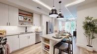 This thoughtfully designed one-bedroom, one-bathroom unit in Austin's vibrant 78704 corridor offers a modern aesthetic with high-end finishes throughout. The open-concept kitchen is a standout, featuring light wood cabinetry, open shelving, a white subway tile backsplash, stainless steel appliances including a French door refrigerator, and a central island with built-in shelving that doubles as a casual dining bar—all anchored by striking matte black pendant lights and a tray ceiling detail. Light wood-tone flooring flows seamlessly into the living room, where a coffered ceiling with recessed lighting and a sculptural chandelier add architectural character. Large windows and glass French doors flood the living space with natural light and provide direct views of lush tree canopy, creating an airy, connected-to-nature ambiance. The bedroom continues the serene palette with expansive windows framing treetop views and clean white walls that complement the warm, curated décor. The bathroom is finished with a wood-framed vanity mirror, dual sinks set in a stone-toned countertop, white cabinetry with matte black hardware, and warm tile accents. A dedicated closet completes this well-appointed, efficiently laid-out residence in the heart of Austin.