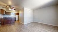 This single-floor unit offers a cohesive and functional layout highlighted by light wood-look flooring that runs throughout the entire space. The living area is a standout feature, showcasing a painted exposed brick accent wall alongside a large window dressed with vertical blinds that allow abundant natural light to fill the room. A ceiling fan adds both comfort and practicality to the space.

The kitchen is well-appointed with warm wood cabinetry that extends to the upper and lower walls, forming an L-shaped configuration complemented by a peninsula with additional storage and counter space. White appliances, including a gas range, dishwasher, and refrigerator, are neatly integrated into the layout. A window above the sink brings in natural light, while a range hood provides ventilation.

The bathroom features a granite-topped vanity with wood cabinetry, textured walls, and a built-in shelving nook, adding both storage and character. Additional storage is accessible throughout the unit. The entry area presents textured walls and a solid door, offering a welcoming and secure entry point. Overall, the space maintains a clean, neutral palette that provides a versatile and move-in-ready environment.