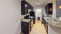 Located at 15705 Colony Oaks Dr in Charlotte, NC, this single-floor residence offers a thoughtfully designed layout that balances functionality and comfort. The open-concept kitchen serves as a central highlight, featuring rich dark cabinetry, granite countertops, a tile backsplash, and stainless steel appliances including a built-in microwave and electric range. A peninsula with pendant lighting extends into the living area, creating a seamless transition between cooking and entertaining spaces. Track lighting illuminates the kitchen corridor, which is finished with light hardwood-style flooring for easy maintenance.

The living area is carpeted and equipped with a ceiling fan, lending a relaxed, comfortable atmosphere. The bedroom continues this aesthetic with plush carpeting, a ceiling fan, and a window dressed with blinds that allows for natural light while maintaining privacy. A door leads to additional storage or closet space, adding to the room's practicality.

The bathroom features a generously sized soaking tub with an overhead shower, framed by clean white tile surround and polished chrome fixtures, creating a bright and functional space. Throughout the home, neutral wall tones and consistent finishes create a cohesive, move-in-ready environment well-suited to Charlotte's vibrant community setting.