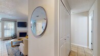 This single-floor residence offers a thoughtfully designed layout that balances comfort and functionality across its key living areas. The entryway greets visitors with textured walls and a decorative round mirror, offering a glimpse into the inviting living space beyond.

The living room serves as the heart of the home, featuring a tile-surround fireplace, a wall-mounted television, and a textured ceiling. The space is bright and welcoming, with room for comfortable seating arrangements.

Adjacent to the living room, the dining area benefits from large windows with views of mature trees outside, allowing ample natural light to fill the space. A pendant light fixture adds a finishing touch overhead.

The kitchen is well-equipped with warm maple cabinetry extending to the ceiling, stainless steel appliances including a refrigerator, range, microwave, and dishwasher, and light tile flooring that ties the space together cohesively.

The bedroom features wood-style flooring, a ceiling fan, and corner windows that provide natural light and outdoor views. A textured ceiling complements the clean, neutral walls throughout.

The bathroom is finished with matching maple cabinetry, a white countertop vanity, a framed mirror, and light tile flooring, maintaining a consistent and clean aesthetic throughout the home.