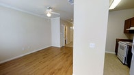 This two-story home offers a clean, well-maintained interior with a thoughtfully designed layout across both levels. The main living area is finished with warm hardwood-style flooring that extends throughout, creating a cohesive and inviting atmosphere. Crown molding adds a refined architectural detail to the living space, while a ceiling fan with a light fixture provides both comfort and practical illumination. Neutral, light-toned walls complement the natural warmth of the flooring, lending the interior a bright and airy feel. Recessed lighting enhances visibility and adds a modern touch to the space. A hallway connects the living area to additional rooms, hinting at a well-organized floor plan with clear transitions between spaces. The entryway and interior doors are finished in white, maintaining a consistent and clean aesthetic throughout. HVAC vents are integrated into the ceiling, ensuring climate control across the home. The overall ambiance is calm and neutral, providing an excellent canvas for personalization. Spanning two floors, this home offers ample room for both daily living and private retreats, making it a versatile and functional residence.