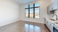 Located at 1720 Nick Nuccio Parkway in Tampa, FL, this efficiently designed one-bedroom, one-bathroom unit offers a thoughtful layout across a single floor. The open kitchen serves as a focal point, featuring contemporary grey flat-panel cabinetry, a herringbone tile backsplash, stainless steel appliances including a refrigerator with ice maker, dishwasher, range, and microwave, all set atop rich dark hardwood flooring that extends throughout the main living areas. Large windows allow generous natural light to fill the space, with views of the surrounding Tampa cityscape.

A well-appointed hallway connects the rooms, highlighted by stylish sliding barn doors with matte black hardware, adding a modern farmhouse touch to the clean, neutral aesthetic. The bedroom features plush carpeting and crisp white walls, offering a quiet retreat. A dedicated closet provides convenient storage. The bathroom is finished with wood-look tile flooring, a combined tub and shower with a sleek black curved rod, and a vanity with matching black hardware, maintaining a consistent design language throughout. The clean, modern finishes and efficient use of space make this unit a functional and attractive residence in the heart of Tampa.