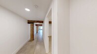 Located at 230 Goldsboro St S in Wilson, NC, this 1-bedroom, 1-bathroom unit masterfully blends industrial character with modern finishes. Polished concrete floors run throughout the entire space, complemented by striking exposed wood beams that trace the length of the hallways and living areas, adding warmth and a sense of history to the clean, white-painted interior.

The open kitchen and living area serves as the heart of the unit, featuring a peninsula with a built-in sink and light quartz countertops, gray shaker cabinetry, and a full suite of stainless steel appliances including a refrigerator, range, and microwave. The living area benefits from natural light streaming through windows framed by an original exposed brick wall, creating a compelling industrial-chic focal point.

The hallway connects the main living spaces to the bedroom, bathroom, and utility room. The bedroom is a well-proportioned, quiet retreat, featuring an overhead exposed beam. The bathroom is cleanly appointed with a tub-shower combo, a vanity with white countertop, and classic penny tile flooring. A dedicated utility room and ample hallway space round out this thoughtfully designed, character-rich unit.