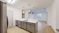 Located at 2200 Ingram Ave in Richmond, VA, this single-floor home offers three bedrooms, two full bathrooms, four closets, and an in-unit laundry area. The open-concept kitchen and living area form the heart of the home, where a sleek kitchen island with a stainless steel sink and white quartz countertops anchors the space. Gray cabinetry with brushed gold hardware and pendant lighting above the island add a contemporary touch, while light wood-style flooring flows seamlessly into the adjacent living area. Elevated clerestory windows alongside a standard window bring in natural light, creating a bright and airy atmosphere. The spacious primary bedroom comfortably accommodates large furniture and features a ceiling fan and its own closet access. Additional bedrooms offer light wood flooring, windows with city views, and ceiling fans. Both bathrooms are finished with the same cohesive design palette — featuring gray vanity cabinetry, white quartz countertops, a rectangular mirror with vanity lighting, tub-shower combinations with white subway tile surrounds, and neutral stone-look tile flooring. The clean, modern aesthetic and thoughtful layout make this home a functional and stylish residence in Richmond.
