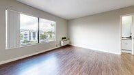 Located on Emelita Street in the Valley Village neighborhood of Los Angeles, this 1-bedroom, 2-bathroom unit offers a well-designed, functional layout across a single floor. The open-concept living and kitchen area is bright and welcoming, anchored by warm hardwood-style flooring and a ceiling fan overhead. A large window fills the living space with natural light while offering views of the surrounding neighborhood, including palm trees characteristic of the LA landscape. The kitchen is efficiently designed in a galley style, featuring white shaker cabinetry, dark countertops, stainless steel appliances including a gas range, microwave, and refrigerator, a skylight for added brightness, and a peninsula with a sink that opens to the living area. The bedroom is carpeted for comfort and includes a window overlooking the neighborhood, and connects to a dedicated walk-in closet outfitted with built-in shelving, hanging rods, and ample storage space. Two full bathrooms serve the unit, one of which includes a tub/shower combination with clean white finishes. The unit's neutral color palette, clean lines, and practical layout create a comfortable and modern living environment well-suited for everyday life in Los Angeles.