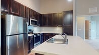Located at 902 Delaney Cir in Brandon, Florida, this single-floor residence offers a thoughtfully designed layout with a cohesive, neutral color palette throughout. The kitchen is a standout feature, boasting rich dark-stained cabinetry that extends to the ceiling for ample storage, crisp light countertops, and a full suite of stainless steel appliances including a refrigerator, electric range, and built-in microwave. A spacious kitchen island with an integrated sink provides additional prep space and opens toward the living area, which features wood-look flooring for a warm, clean aesthetic. The bedrooms are finished with plush wall-to-wall carpeting, ceiling fans, and large windows dressed with white blinds that invite natural light and offer views of the surrounding greenery. Select rooms feature elegant crown molding, adding a refined architectural detail. The bathrooms are well-appointed with dark-framed vanity mirrors, dark cabinetry with light countertops, tile flooring, and one bathroom includes a glass-enclosed shower. The overall ambiance is clean, contemporary, and move-in ready, presenting a comfortable and functional living environment in the Brandon, FL area.
