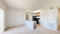 Located at 4401 Truxel Rd in Sacramento, CA, this single-floor, one-bedroom unit offers a thoughtfully organized layout across a compact footprint. The open-concept living, dining, and kitchen area forms the heart of the space, where light-toned carpet flows through the living and dining zones, while wood-look flooring defines the kitchen area. The kitchen features flat-front cabinetry in a warm taupe finish, a peninsula with a sink and white countertop, and black appliances including a refrigerator and range. Natural light fills the living area through multiple windows fitted with blinds and a sliding glass door with vertical blinds that leads to the exterior. A hallway connects the main living area to the private bedroom, which is carpeted and includes a sliding-door closet. Additional closet storage is available elsewhere in the unit. The bathroom presents a clean, modern aesthetic with wood-toned cabinetry, a white countertop vanity, a large mirror, and wood-look tile flooring. A dedicated laundry area and an entrance with an accessible electrical panel round out the functional layout, making this a well-equipped and efficiently designed unit.