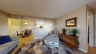 This single-floor, two-bedroom, two-bathroom residence in Rockridge offers a practical and comfortable layout designed for everyday living. The living area is an inviting space anchored by tile flooring partially covered by a geometric-patterned area rug, with warm neutral walls throughout. A pass-through window connects the living room to the galley-style kitchen, which is equipped with black appliances—including a refrigerator, electric range, and dishwasher—white cabinetry, and granite-look countertops. Adjacent to the kitchen, a dedicated dining nook features tile flooring and overhead pendant lighting, creating a defined space for meals. The primary bedroom is generously sized with tile flooring, a window admitting natural light, and direct access to a walk-in closet outfitted with shelving and hanging rods. The bathrooms feature tile floors, white vanities with stone-look countertops, and shower-tub combinations. Neutral, warm-toned walls carry consistently throughout the unit, contributing to a cohesive and calm ambiance. The overall layout flows logically from the communal living and dining spaces through to the private bedrooms, offering a well-organized and functional home.