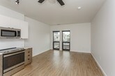 This single-floor unit showcases a clean, contemporary design throughout its open-concept layout. Light hardwood flooring extends across the main living area, creating a bright and cohesive aesthetic that complements the crisp white walls and modern finishes.

The kitchen is efficiently designed with two-tone cabinetry—combining white upper cabinets with warm wood-grain lower cabinets—and is equipped with a full suite of stainless steel appliances, including a refrigerator, electric range, built-in microwave, and dishwasher. A white quartz countertop and subway tile backsplash add a polished, contemporary touch. Track lighting above the kitchen and a ceiling fan over the living area provide both functional illumination and airflow.

A dedicated in-unit laundry closet houses a stacked washer and dryer, offering added convenience. The bathroom features a wood-toned vanity with a white quartz countertop and a glass-enclosed walk-in shower with large-format gray tile, lending a spa-like quality to the space.

The living area is generously proportioned and benefits from large windows that frame city views, filling the space with natural light. The overall ambiance is contemporary, clean, and move-in ready.