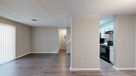 This single-story, 1-bedroom, 1-bathroom residence offers a thoughtfully designed layout that maximizes its compact footprint. Throughout the home, durable wood-look flooring in warm, neutral tones creates a cohesive and inviting atmosphere, complemented by soft beige walls and clean white trim.

The open-concept living room is a standout space, anchored by a classic white brick fireplace that serves as a focal point. A large sliding glass door fitted with vertical blinds floods the room with natural light and provides access to the outdoors. A pendant light near the kitchen pass-through adds a warm glow to the dining area.

The galley-style kitchen is efficiently arranged with ample white cabinetry, light countertops, a stainless steel sink, and black appliances including a range and refrigerator. A mosaic tile backsplash adds a decorative touch behind the range.

The bedroom is a comfortable, well-sized room featuring the same wood-look flooring, neutral walls, and a dedicated closet. A hallway connects the bedroom to the full bathroom, which includes a clean, white tub-shower combination.

Textured ceilings are present throughout, and a hallway with additional storage leads to the front entry. The overall aesthetic is clean, neutral, and move-in ready.
