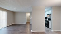 This single-story, 1-bedroom, 1-bathroom residence offers a thoughtfully designed layout that maximizes its compact footprint. Throughout the home, durable wood-look flooring in warm, neutral tones creates a cohesive and inviting atmosphere, complemented by soft beige walls and clean white trim.

The open-concept living room is a standout space, anchored by a classic white brick fireplace that serves as a focal point. A large sliding glass door fitted with vertical blinds floods the room with natural light and provides access to the outdoors. A pendant light near the kitchen pass-through adds a warm glow to the dining area.

The galley-style kitchen is efficiently arranged with ample white cabinetry, light countertops, a stainless steel sink, and black appliances including a range and refrigerator. A mosaic tile backsplash adds a decorative touch behind the range.

The bedroom is a comfortable, well-sized room featuring the same wood-look flooring, neutral walls, and a dedicated closet. A hallway connects the bedroom to the full bathroom, which includes a clean, white tub-shower combination.

Textured ceilings are present throughout, and a hallway with additional storage leads to the front entry. The overall aesthetic is clean, neutral, and move-in ready.