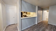 This well-appointed 2-bedroom, 2-bathroom single-floor residence offers a practical and comfortable layout across a modest but efficiently organized footprint. The open-concept main living area seamlessly combines the living room, dining room, and kitchen into one cohesive space. The kitchen features a pass-through counter with a white surface, cabinetry, a range with overhead ventilation, and a refrigerator, making it both functional and accessible from the main living area. The living room is highlighted by a wood-burning fireplace with a tiled hearth and shiplap-style surround, complemented by large vertical-blind-covered sliding doors that allow ample natural light. Durable wood-look flooring runs throughout the main living areas, while plush carpet adds warmth to the bedrooms. The primary bedroom includes a spacious walk-in closet with built-in shelving and hanging rods. Additional closets throughout the unit provide generous storage. Both bathrooms feature tub-shower combos with white tile surrounds. A dedicated laundry area with washer hookups and shelving adds everyday convenience. A pantry rounds out the home's practical storage offerings. Textured ceilings are present throughout the space.