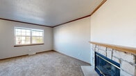 This well-organized multi-level home spans three floors and offers 2 bedrooms and 3 bathrooms, providing a practical and functional layout for everyday living. The main living level is the heart of the home, anchored by a spacious living room with soft carpet flooring, warm crown molding, a textured ceiling, and a corner stone fireplace with a wood mantel and glass doors — a standout architectural feature that adds character to the space. A window allows natural light to filter in, brightening the room.

The kitchen is thoughtfully designed with a central island offering additional prep and counter space, white cabinetry trimmed with wood accents, white appliances, and durable flooring. A pendant light fixture and flush-mount ceiling lights illuminate the space effectively.

The two bedrooms are carpeted and generously sized, each featuring sliding or hinged closet doors with built-in shelving for organized storage. Both rooms include windows that bring in natural daylight. The primary bedroom is notably spacious and connects to a dedicated walk-in closet with wire shelving systems.

Three bathrooms are distributed throughout the home, each finished with wood-toned vanities, light countertops, wood-look flooring, and clean, functional fixtures. Carpeted staircases with wooden handrails connect the three levels, providing easy vertical circulation throughout the home.