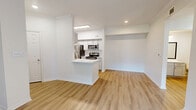 This thoughtfully designed single-floor residence offers a comfortable and functional layout across a well-utilized footprint. The open-concept living and kitchen area serves as the heart of the home, where light wood-style flooring flows seamlessly throughout. The living room is highlighted by a striking tiled fireplace with a rustic wood mantel, built-in shelving, crown molding, a ceiling fan, and a sliding glass door that invites natural light and provides outdoor views. The kitchen is efficiently appointed with white cabinetry, a clean white countertop peninsula, a tile backsplash, and a full suite of stainless steel appliances including a refrigerator, electric range, microwave, and dishwasher. The bedroom offers a cozy, carpeted retreat with natural light filtering in through windows with outdoor greenery views. Three closets provide generous storage throughout the unit. The bathroom features a combined shower and soaking tub with brushed nickel fixtures, a vanity with storage, and wood-style flooring. A dedicated utility room completes the layout, adding practical functionality. The overall aesthetic is clean, bright, and modern with a neutral palette throughout.
