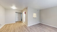 Located at 6500 W 43rd St in Houston, TX, this one-bedroom, one-bathroom unit is thoughtfully laid out across a single floor, making efficient use of its compact footprint. Light wood-style flooring runs throughout the living areas and hallway, lending a clean, cohesive look to the space. The living room is bright and open, featuring a large window that allows natural light to fill the room while offering views of the surrounding area, including glimpses of the Houston skyline. A pass-through window connects the living area to the kitchen, enhancing the sense of openness between the two spaces. The kitchen is equipped with white cabinetry, granite-style countertops, a full-size refrigerator, and a sink, providing all the essentials for daily use. A hallway leads from the main living area to the private bedroom, which features plush carpeting and a dedicated window for natural light. The bedroom connects to a spacious walk-in closet with built-in shelving, offering ample storage. The full bathroom includes a tub-shower combination, a white vanity with granite-style countertop, and a large mirror. Neutral warm-gray tones throughout the unit create a calm and inviting atmosphere.