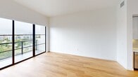 This sleek 720 square foot apartment offers a perfect blend of modern design and urban living. The single-bedroom unit boasts an open floor plan that maximizes space and light. Floor-to-ceiling windows dominate the living areas, providing breathtaking panoramic views of the city skyline and surrounding landscape.

The kitchen is a testament to contemporary design, featuring gleaming white cabinetry contrasted with warm wood lower cabinets. High-end stainless steel appliances, including a built-in microwave and spacious refrigerator, complement the sleek countertops. Under-cabinet lighting adds a touch of sophistication.

The bathroom is a luxurious retreat, showcasing marble-like tiling from floor to ceiling. A glass-enclosed shower and modern vanity with ample storage space create a spa-like atmosphere. The bedroom, while compact, offers plenty of natural light and continues the apartment's clean, minimalist aesthetic.

Throughout the space, light hardwood flooring adds warmth and ties the rooms together. The neutral color palette and abundance of natural light create an airy, expansive feel despite the apartment's efficient footprint. This penthouse unit, located on the 52nd floor, provides an unparalleled urban living experience with its modern amenities and stunning views.