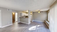 This single-floor residence offers a well-organized layout that balances open living spaces with functional private rooms. The main living and dining area is bright and spacious, featuring light grey laminate flooring, neutral-toned walls, and a ceiling fan overhead. A textured popcorn ceiling adds a classic touch throughout the home. The kitchen is designed with practicality in mind, featuring white cabinetry, a built-in microwave, an electric range, a full-size refrigerator, and a double sink. A raised breakfast bar peninsula connects the kitchen to the living area, creating a seamless open-concept flow ideal for both everyday living and entertaining. A sliding glass door with vertical blinds opens to a private balcony, allowing natural light to fill the main living space. The bedrooms are generously sized, each featuring the same durable laminate flooring and neutral wall tones. One bedroom includes an arched window that invites additional natural light, while another features a wide sliding-door closet for ample storage. The bathroom is clean and efficient, complete with a tiled shower-tub combination, a toilet, and a wide vanity with a granite-style countertop and a large mirror above.