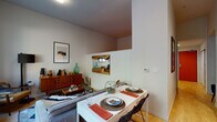 This single-floor residence offers a well-organized and stylish layout that balances function with comfort. The open-plan living and dining area serves as the heart of the home, featuring light wood flooring, neutral walls, and a seamless flow between spaces. A compact dining table with woven placemats sits adjacent to the living area, which includes a mid-century modern credenza and curated wall art, lending the space a warm, collected character.

The kitchen is fully equipped with stainless steel appliances, including a gas range, microwave, and refrigerator. White upper cabinetry contrasts with dark lower cabinets, and a classic white subway tile backsplash adds a clean, timeless detail. The layout maximizes counter space and storage efficiently.

The bedroom is a cozy, intimate retreat featuring a striking reclaimed wood herringbone headboard as its focal point. Warm ambient lighting from wall-mounted and bedside fixtures creates a relaxed atmosphere, while the high ceiling adds a sense of openness to the room.

The bathroom is finished with light flooring, a dark vanity with a white countertop, a large mirror, and a shower with a white curtain. Patterned towels and framed wall art add personality to the otherwise clean, minimal space. Overall, the residence presents a cohesive and livable environment with thoughtful design details throughout.