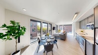 Located in Portland's vibrant Pearl District, this contemporary unit at 1315 NW Johnson St offers a thoughtfully designed open-concept layout filled with natural light. Light-toned hardwood flooring flows throughout, complementing the clean, modern aesthetic of the bright white walls and ceilings.

The entry hallway welcomes you with wall art and a built-in bench with storage, leading into the main living area. Floor-to-ceiling windows on multiple sides flood the dining and living spaces with sunlight while framing dynamic urban views of the surrounding streetscape and neighboring brick architecture. The dining area accommodates a round table with seating for four, positioned to take full advantage of the expansive window views.

The kitchen features sleek gray cabinetry, a white countertop, and a full suite of stainless steel appliances, including a refrigerator, electric range, and over-the-range microwave, all illuminated by modern linear lighting overhead.

The living area is generously sized, with wall-mounted TV flanked by large windows offering additional city views. A wall-mounted mini-split system provides efficient climate control throughout the space.

The bedroom is a calm retreat featuring a closet that also houses a convenient in-unit washer. The bathroom is clean and modern, with wood-look flooring, a full tub and shower combination, and a vanity with a light countertop.