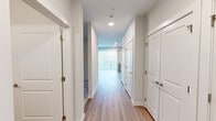 This thoughtfully designed one-bedroom, one-bathroom unit offers a comfortable and modern living experience across a single floor. The open-concept layout seamlessly connects the kitchen and living room, creating a bright and functional shared space. Large windows with vertical blinds and horizontal slat blinds allow abundant natural light to fill the interior, enhancing the clean, neutral aesthetic throughout.

The kitchen is a standout feature, equipped with stainless steel appliances including a refrigerator with ice maker, dishwasher, and microwave. Light wood-tone cabinetry pairs elegantly with white quartz countertops and a marble-style subway tile backsplash, delivering a sleek, contemporary look. Light wood-style plank flooring runs through the main living areas, adding warmth and continuity.

A stylish barn-style sliding door connects the living area to the hallway, adding an architectural detail that sets this unit apart. The bedroom is carpeted with a subtle geometric pattern, features a ceiling fan with light, and connects directly to the bathroom for added convenience.

The bathroom includes a full soaking tub with shower combo, a single vanity with modern cabinetry, and clean white finishes throughout. The well-lit hallway with recessed lighting provides a welcoming transition between all rooms, completing this functional and modern living space.