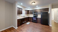 Located at 617 N Notre Dame Ave in South Bend, Indiana, this well-appointed 2-bedroom, 2-bathroom single-floor home offers a functional and comfortable layout throughout. The open-concept living and kitchen area serves as the heart of the home, featuring rich hardwood-style flooring that extends seamlessly through the main living spaces. Large windows allow natural light to fill the area, creating a bright and welcoming atmosphere.

The kitchen is thoughtfully designed with dark espresso-toned cabinetry providing ample storage, light-colored countertops, a double stainless steel sink, and a full suite of black appliances including a refrigerator, electric range with over-the-range microwave, and dishwasher. Recessed lighting accents the space effectively.

Both bedrooms offer a quieter retreat with soft wall-to-wall carpeting and windows fitted with blinds for privacy and light control. The spacious primary bedroom provides a generous footprint for comfortable furnishing. A hallway connects the private areas of the home efficiently.

The two bathrooms are well-equipped, each featuring a tub/shower combination, vanity with sink, and hardwood-style flooring. Neutral, warm-toned walls throughout the home create a cohesive and inviting aesthetic that complements the varied flooring choices across each room.
